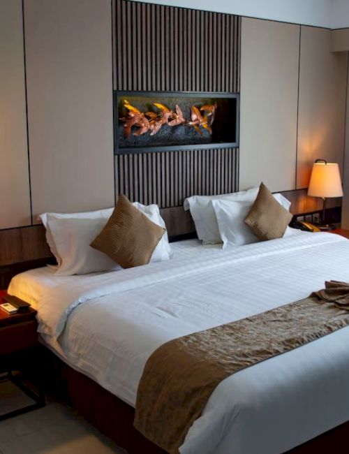 A hotel room featuring a large bed with brown accents, two bedside lamps, modern decor, and a window with curtains.