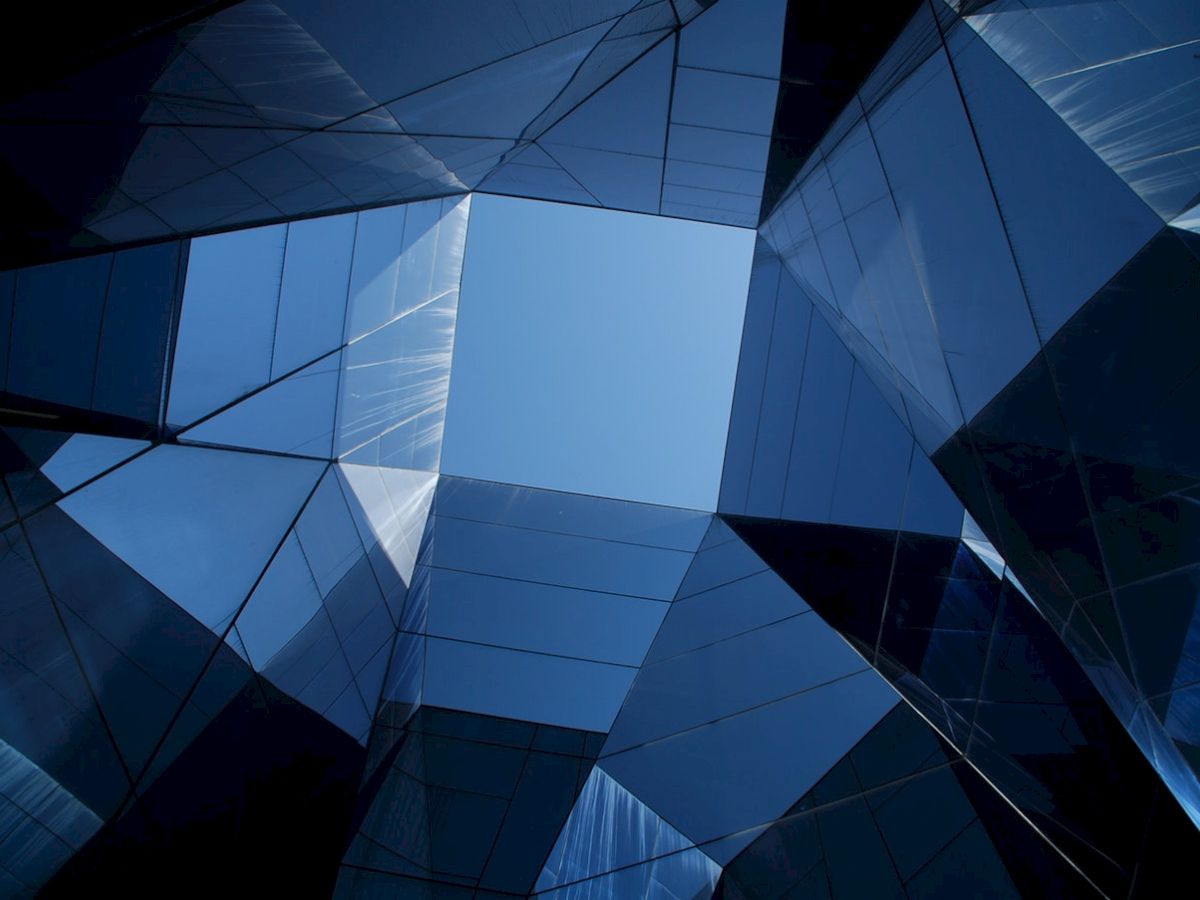 Abstract view of skyscrapers creating a geometric pattern against the blue sky, with reflective glass surfaces.