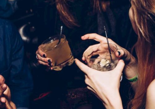 People are enjoying a social gathering, holding drinks, and sharing laughter.