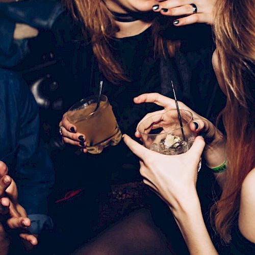 People are enjoying a social gathering, holding drinks, and sharing laughter.
