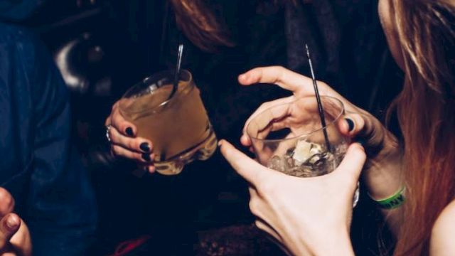 People are enjoying a social gathering, holding drinks, and sharing laughter.