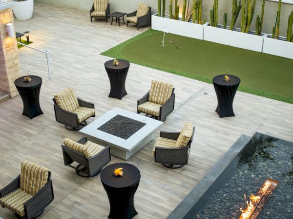 The image shows an outdoor patio with wicker chairs, a fire pit, tall tables, and a rectangular pool. A sign reads "California."