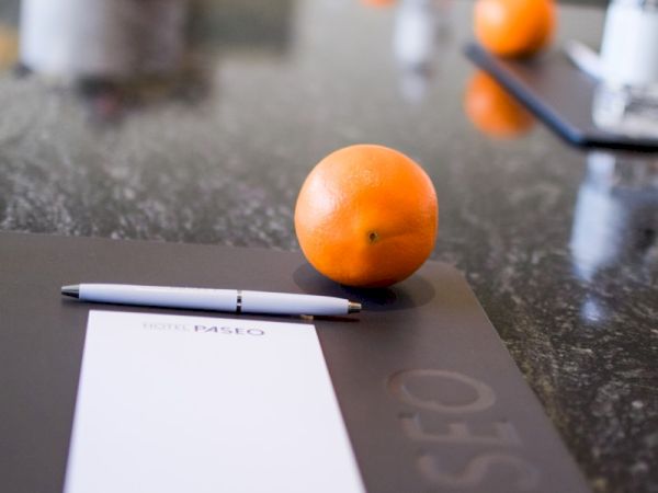 The image shows a table set with notepads, pens, and oranges, possibly in a meeting or conference setting.