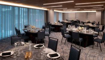 A banquet hall setup with round tables, elegant place settings, and soft ambient lighting.