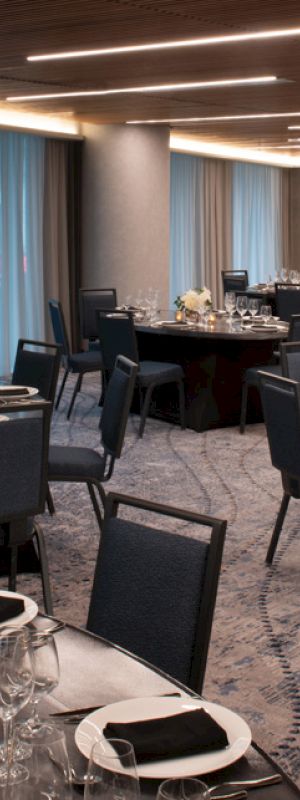A banquet hall with round tables set for dining, featuring elegant table settings and dim lighting, ready for an event or gathering.